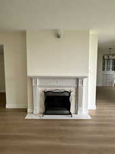 Detailed view of a fireplace with hearth, wood- look finished floors, baseboards