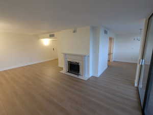 Unfurnished living room with wood finished floors, a high end fireplace, and baseboards