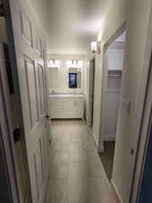 Full bathroom featuring marble finish floors, double vanity, baseboards, and a spacious closet