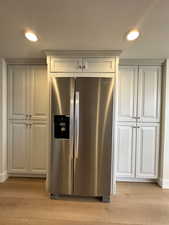 Kitchen featuring stainless steel refrigerator with ice dispenser, light wood-style flooring, baseboards, and a textured ceiling