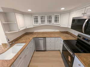 Kitchen featuring stainless steel appliances, a sink, white cabinets, light wood finished floors, and recessed lighting