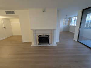 Unfurnished living room featuring wood  style finished floors, a chandelier, a premium fireplace, and baseboards