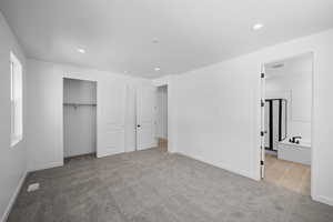Unfurnished bedroom featuring carpet, baseboards, recessed lighting, a closet, and ensuite bath