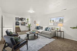 Carpeted living area featuring stairs, a textured ceiling, and baseboards