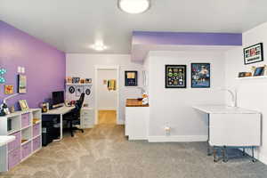 Home office featuring light carpet and baseboards