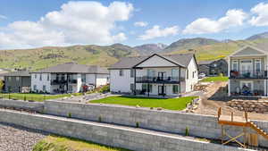 Back of property featuring a residential view, a patio area, a mountain view, and a balcony