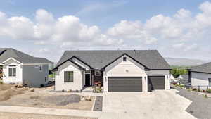 View of front of home with board and batten siding, an attached garage, concrete driveway, and roof with shingles