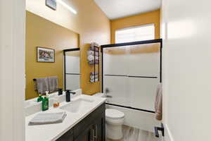 Main floor Bathroom with vanity, wood finished floors, and enclosed tub / shower combo
