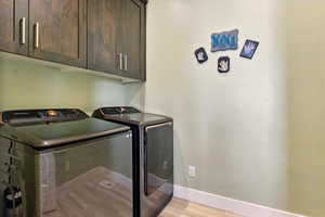 Laundry area featuring cabinet space, washing machine and dryer and light wood-style flooring