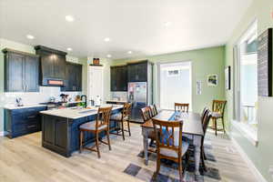 Kitchen featuring appliances with stainless steel finishes, a kitchen breakfast bar, light countertops, backsplash, and light wood-style floors