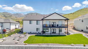 Back of house featuring a patio area, a mountain view, a balcony, and a vegetable garden.