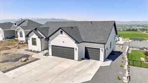 View of front of home featuring driveway, a shingled roof, a mountain view, and a garage