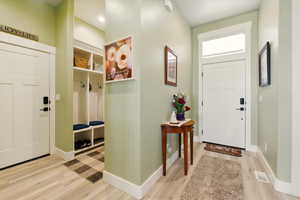 Foyer entrance featuring light wood-style floors and baseboards. Mud room off of garage.