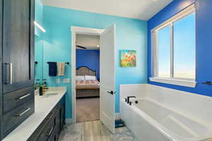 Ensuite bathroom featuring wood finished floors, vanity, a bath and separate shower.