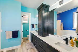 Primary Bathroom with double vanity,  plenty of natural light, and wood finished floors