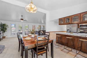 Dining area with vaulted ceiling, a chandelier, light carpet, and ceiling fan