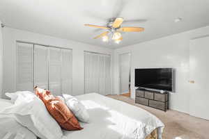 Bedroom featuring two closets, carpet floors, and a ceiling fan