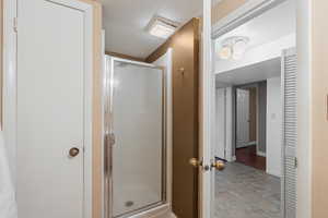 Full bathroom with a textured ceiling and a stall shower