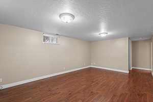 Basement featuring a textured ceiling and dark wood-style flooring