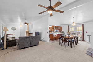 Dining space featuring healthy amount of natural light, light carpet, ceiling fan, and lofted ceiling