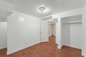 Unfurnished bedroom with a textured ceiling, dark wood-style flooring, and a closet