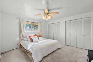 Bedroom with two closets, carpet, and ceiling fan