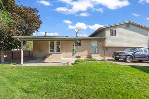Split level home featuring entry steps, brick siding, a patio area, and a front yard