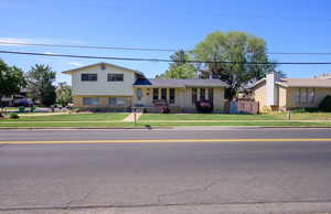 Split level home featuring a front lawn, brick siding, and covered porch