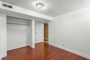 Unfurnished bedroom with dark wood-style floors and a closet