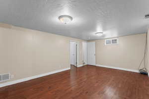 Basement featuring a textured ceiling and dark wood finished floors