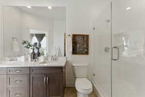 Full bathroom with double vanity, a shower stall, toilet, and tile patterned floors