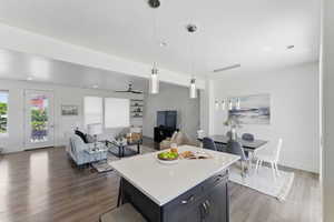 Kitchen featuring dark wood-type flooring, light countertops, decorative light fixtures, a center island, and baseboards