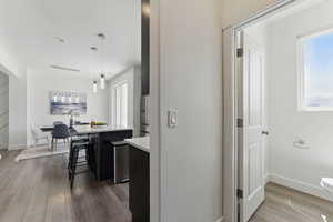 Kitchen featuring dark wood finished floors, light countertops, a breakfast bar area, a kitchen island, and decorative light fixtures