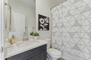 Bathroom featuring toilet, vanity, and shower / bath combo with shower curtain