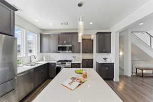 Kitchen featuring appliances with stainless steel finishes, a sink, dark wood-type flooring, light countertops, and dark brown cabinetry