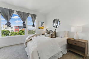 Carpeted bedroom featuring baseboards and lofted ceiling