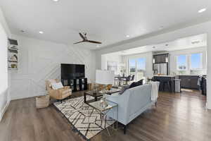 Living room with plenty of natural light, dark wood-type flooring, ceiling fan, a decorative wall, and recessed lighting