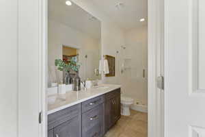 Full bathroom featuring a shower stall, toilet, double vanity, tile patterned flooring, and a walk in closet