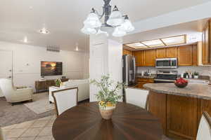 Dining room with light tile patterned flooring, a chandelier, and light colored carpet. Photo has been virtually staged.