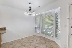Unfurnished dining area with light tile patterned flooring and a chandelier