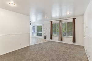 Unfurnished room with light colored carpet, light tile patterned floors, and a wainscoted wall