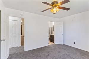 Unfurnished bedroom featuring light colored carpet, connected bathroom, and ceiling fan