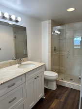 Guest Bathroom with wood finished floors, vanity, a shower stall, and a textured ceiling