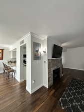 Living area with a textured ceiling, ornamental molding, wood finished floors, a tile fireplace, and baseboards