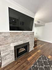 Detailed view of crown molding, a fireplace, wood finished floors, baseboards, and a textured ceiling