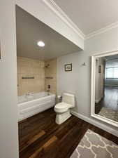 Full bath featuring toilet, hardwood / wood-style flooring, bathing tub / shower combination, and ornamental molding