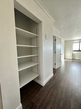 Bedroom hall to in-suite bath featuring ornamental molding, wood finished floors, and a textured ceiling