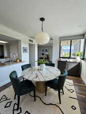 Dining space with dark wood-type flooring and crown molding