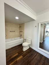 Full bath featuring wood finished floors, ornamental molding, and tiled tub / shower combination
