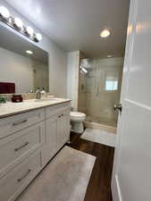 Bathroom featuring a stall shower, toilet, vanity, wood finished floors, and recessed lighting